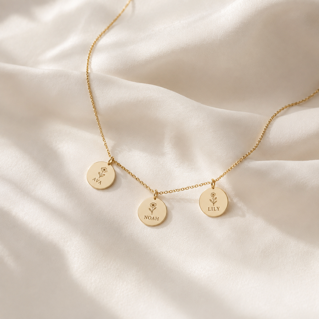 Gold necklace with three engraved name pendants on cream silk