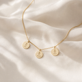 Gold necklace with three engraved name pendants on cream silk