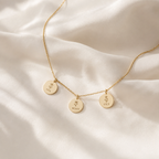 Gold necklace with three engraved name pendants on cream silk