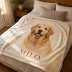 A blanket printed with a golden retriever portrait and the name Milo, spread across a bed with cream linen