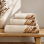 Three printed blankets folded and stacked in increasing sizes on an oak bench
