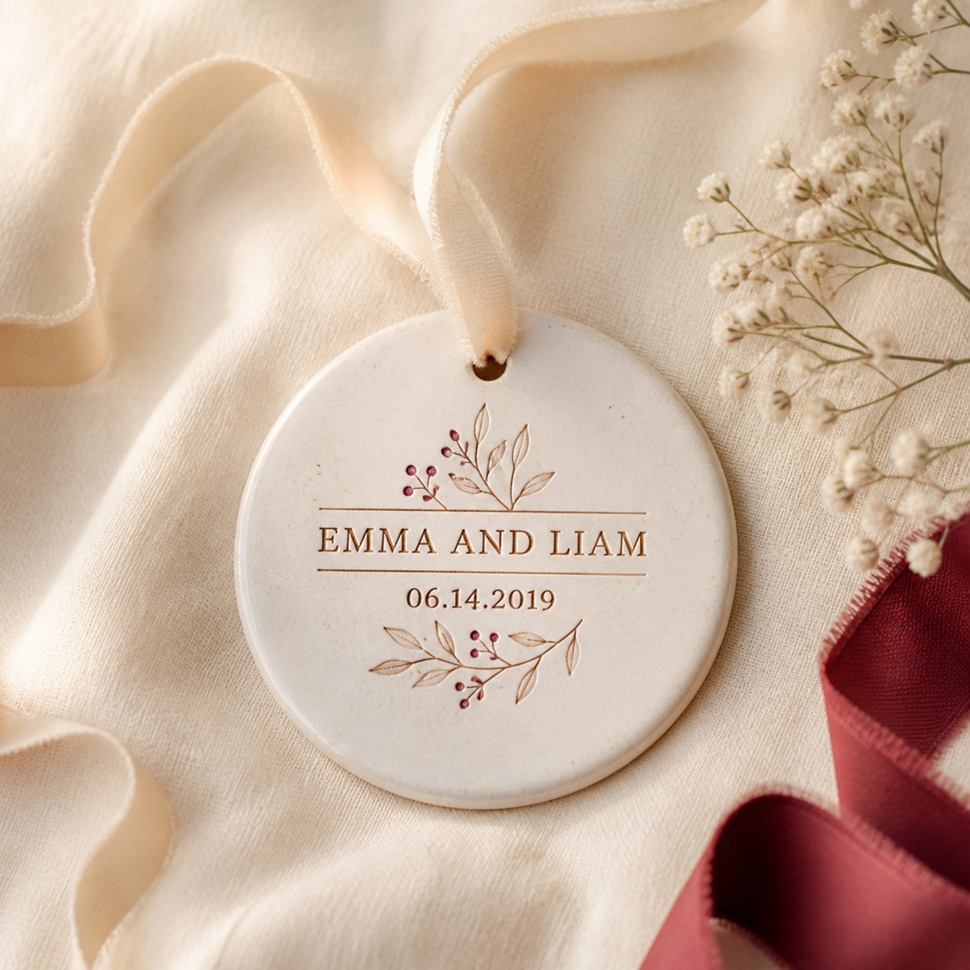 A ceramic couple ornament on cream linen with a cotton ribbon, dried flowers and a plum ribbon