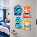 Four personalized nautical door sign magnets displayed on a cruise cabin door