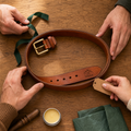 Personalized brown leather belt with brass buckle and engraved mountain name detail on a wooden table