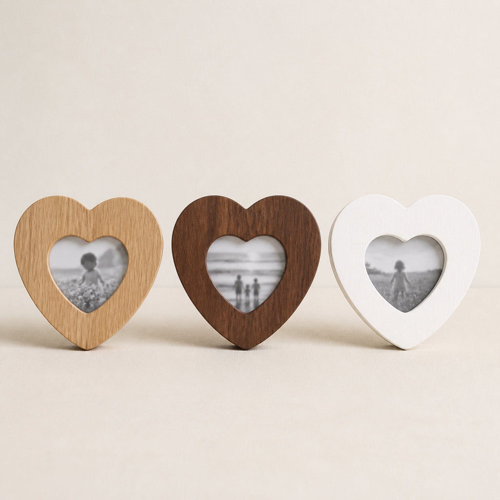 Three heart-shaped photo frames side by side in natural oak, walnut and white