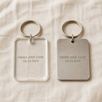 The same engraved keychain in clear acrylic and in brushed stainless steel, side by side for comparison