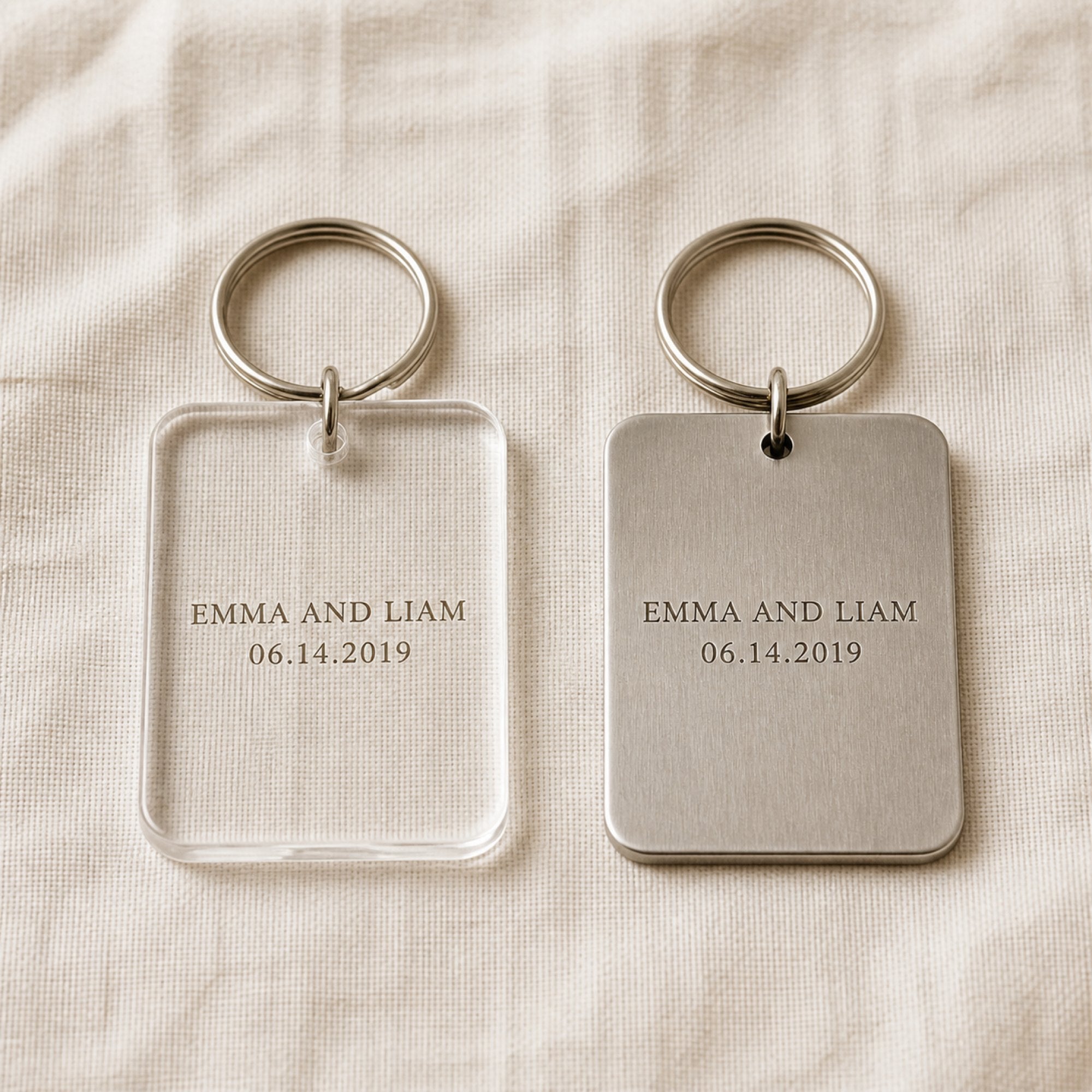 The same engraved keychain in clear acrylic and in brushed stainless steel, side by side for comparison
