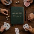 Deep green personalized family game-night leather scorebook surrounded by six hands, playing cards and ivory dice on a walnut table