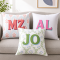 Personalized dorm pillows with colorful shadow initials on a neutral sofa