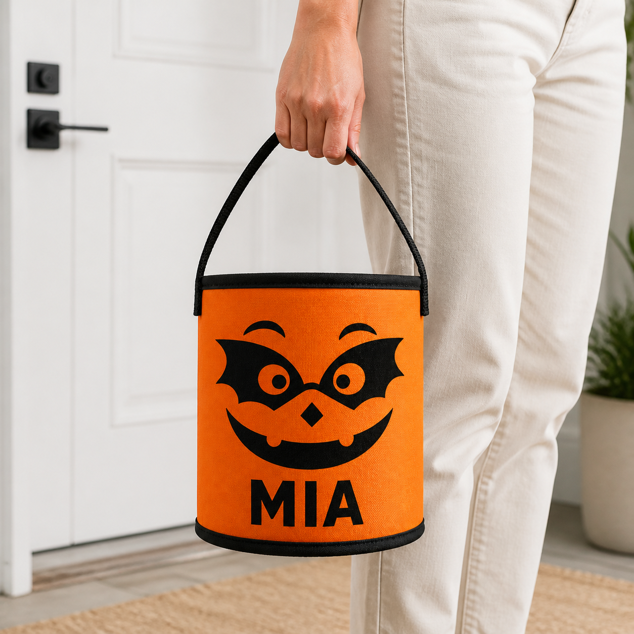 Adult carrying orange MIA personalized Halloween treat basket by the handle